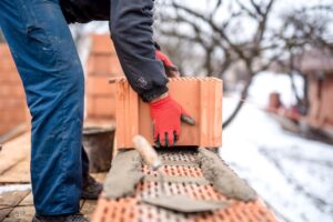 bricklayer working with bricks, cement, mortar for building new house